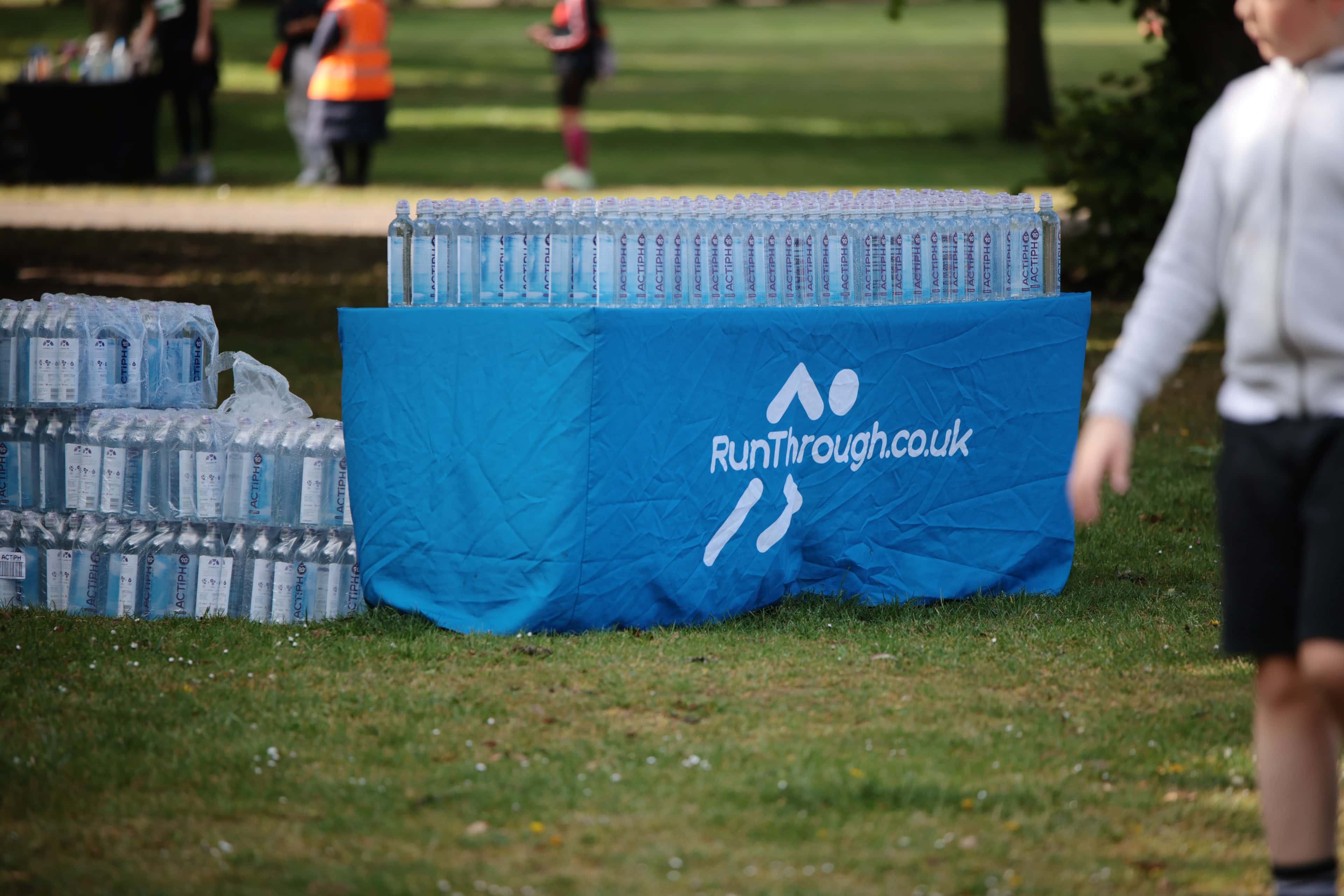 A RunThrough water station being set up by volunteers in hi-vis before a race